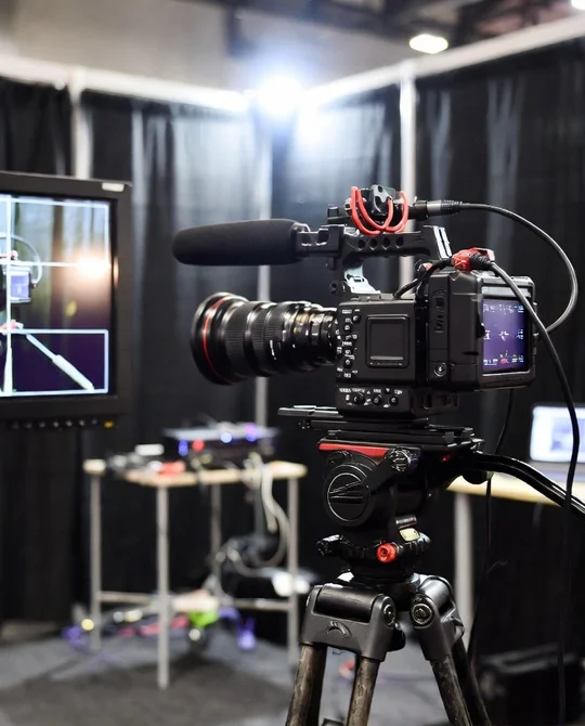 Фотограф и оператор просматривают отснятый материал на ноутбуке у стенда